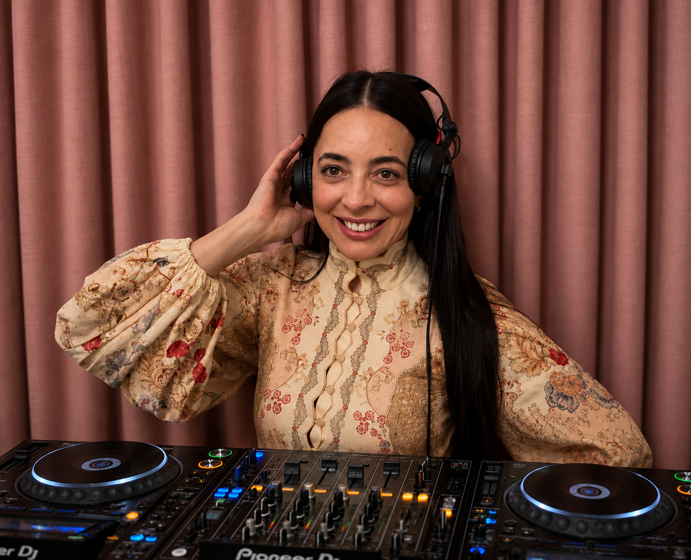 JoNisha smiling behind the DJ decks wearing headphones at a Perth venue